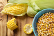 Bowl with kernels and fresh corn cob on wooden background