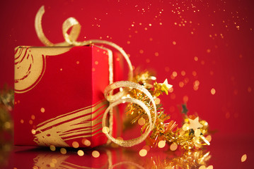 Wall Mural - red gift box with golden ribbons on red holiday background with twinkle bokeh light. merry christmas