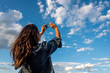 © Bisual Studio/Stocksy - Beauty young woman taking pictures of a cloudy sky with a smartphone
