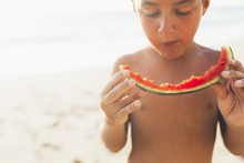 Boy Eating A Piece Of Watermelon At The Beach.