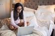 © Daxiao Productions/Stocksy - Young hispanic indian woman checking emails in cosy bedroom