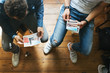 © Julien L. Balmer/Stocksy - Overhead Shot of Two Caucasian Men Sitting in Living Room and Looking at Art Prints