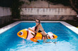 © Susana Ramirez/Stocksy - Funny young woman on top of a mattress fish in the pool