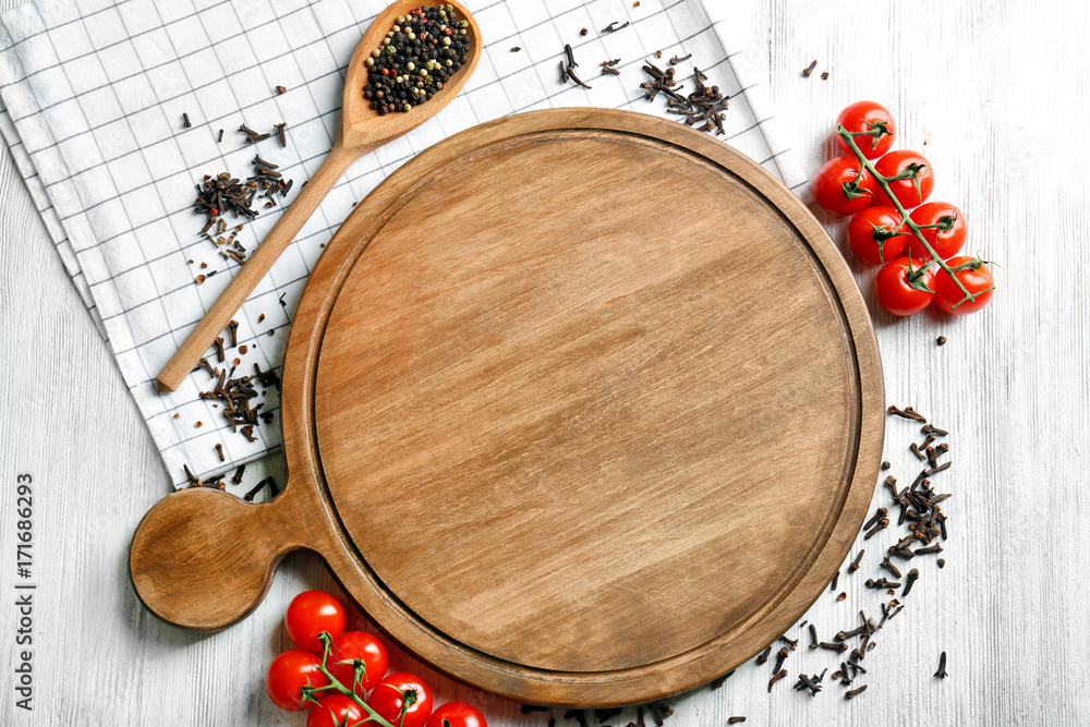 Wooden board and tomatoes with spices on kitchen table. Cooking classes concept