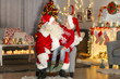 © Africa Studio - Happy little boy sitting on Santa's lap in room with beautiful Christmas decorations