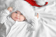 Cute little baby in Santa hat on white sheet