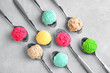 Composition with colorful scoops of ice-cream in spoons on light background