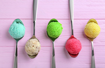 Wall Mural - Composition with colorful scoops of ice-cream in spoons on wooden background