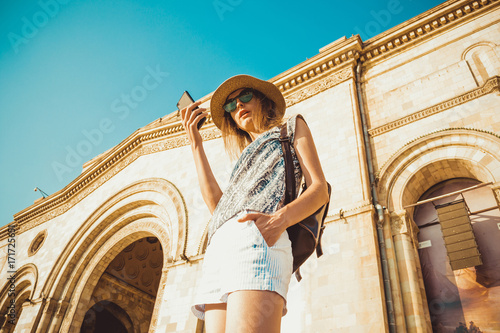 Fotografie, Tablou Woman tourist in hat with backpack using gps navigation on mobile phone