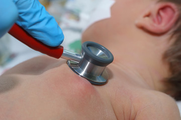 Doctor holding stethoscope in his hand and doing auscultation newborn baby on breathing machine