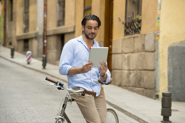 man smiling using internet with digital tablet pad on vintage cool retro bike