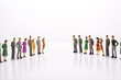 © Wisiel - Miniature people in two lines across to each other over white background.