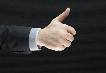 Businessman showing OK sign with his thumb up isolated with black background. Success business deal. Businessman in a suit shows a sign ok fingers of two hands 