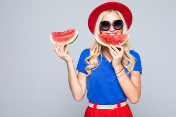 Young blonde woman holding two slice of watermelon in hands and smiling happy wearing in color clothes, summertime concept and mood, over gray background