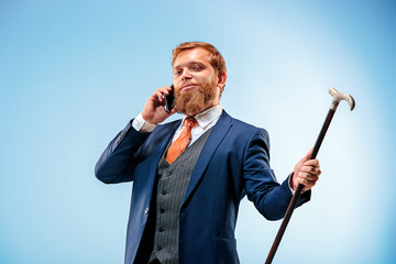 The barded man in a suit holding cane.
