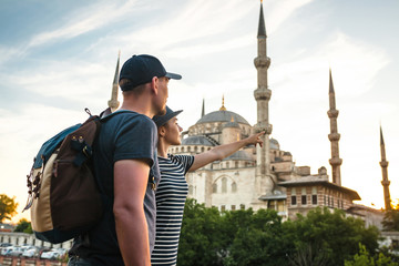 A pair of travelers near the world-famous Blue Mosque in Istanbul, Turkey. The girl shows direction.