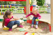 Conflict On The Playground. Two Kids Fighting Over A Toy Shovel In The Sandbox