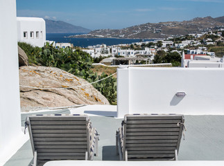 relax per due/ due sdraio sul balcone come sfondo la città di mykonos 