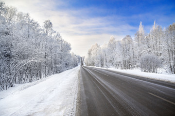 Canvas Print - winter landscape with asphalt road,forest and blue sky