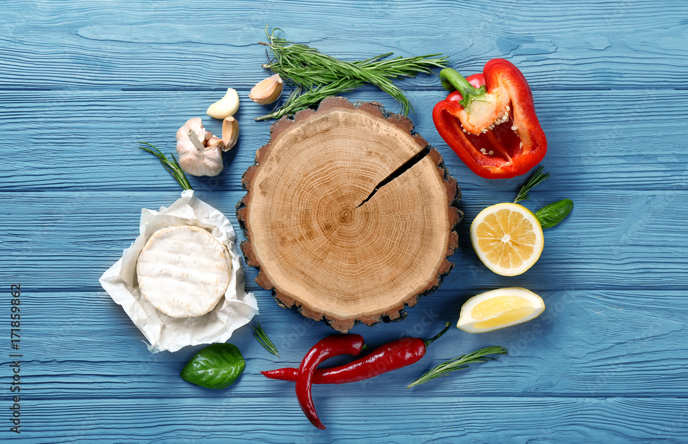 Composition with wooden board, soft cheese and vegetables on table