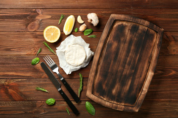 Composition with wooden plate and ingredients on table