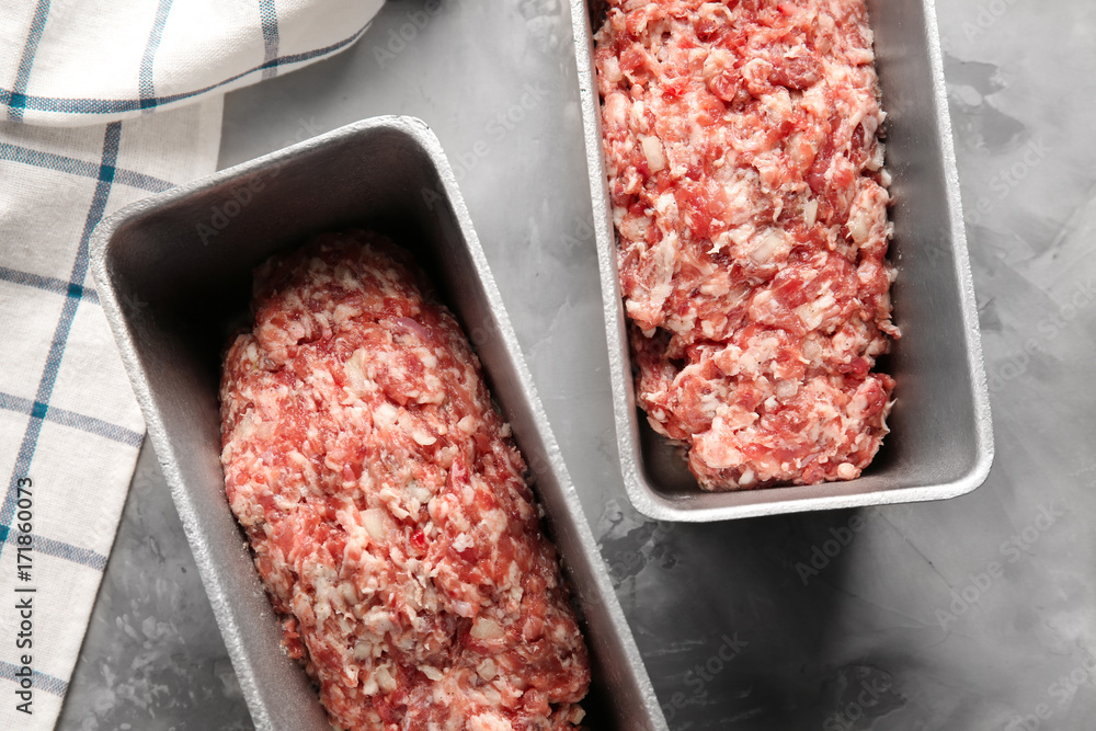 Baking dishes with raw turkey meatloaf on table
