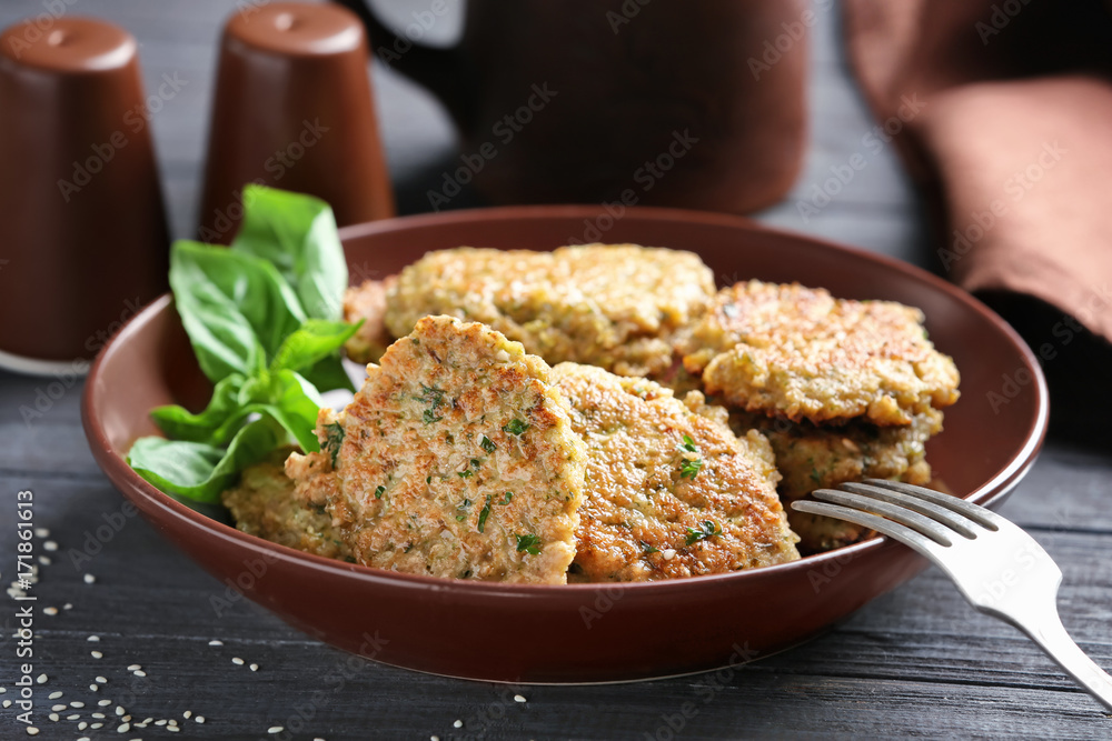 Delicious broccoli pancakes served with fresh basil leaves on brown plate in kitchen
