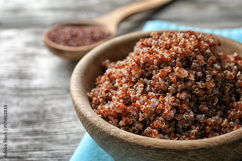 Bowl with boiled quinoa grains on wooden table