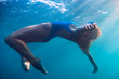 © artifirsov - Woman floating in underwater, blue ocean.