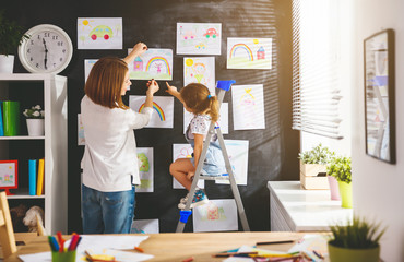 Wall Mural - Mother and child girl hang their drawings on wall