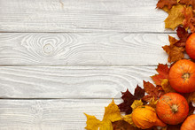 Autumn Leaves And Pumpkins Over Old Wooden Background