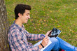 © Pereginskaya - young men student sitting  in the park next to the tree with the tablet in his hands