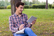 © Pereginskaya - young men student sitting  in the park next to the tree with the tablet in his hands