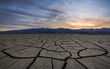 Sunset with clouds over a dry, cracked and scorched foreground