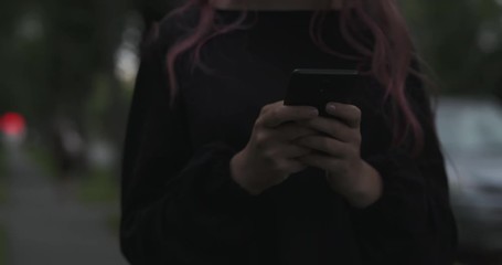 Wall Mural - handheld shot of female teen using smartphone on the street at night