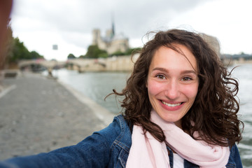 young woman on holidays in paris taking selfie in front on notre dame - tourism concept