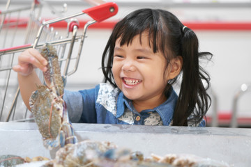 asian children cute or kid girl holding and choose fresh horse crab in ice tray and fun with smile w
