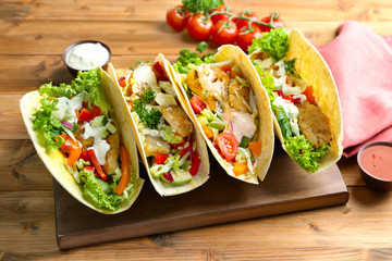 Poster - Wooden board with tasty fish tacos and sauces on table