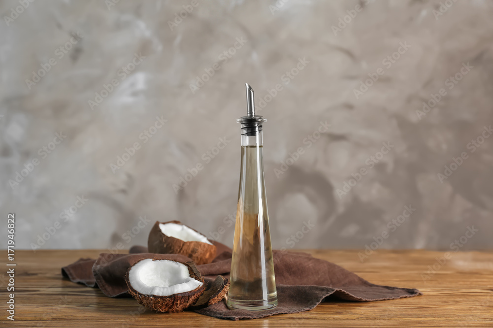 Ripe coconut and bottle with oil on wooden table