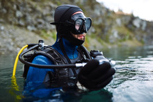 Male Diver In Wetsuit Checking Equipments Before Immerse