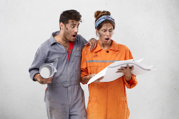 Wall Mural - People, facial expressions and astonishment. Male and female architects in casual clothes, hold blueprint, look with great surprisment, have much work. Repairman and his wife do renovation plan