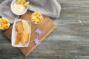 Wall Mural - Tasty fried fish and potato chips on wooden table