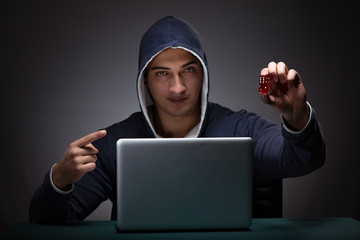 Wall Mural - Young man wearing a hoodie sitting in front of a laptop computer