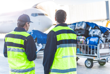 Workers controlling luggage in airdrome