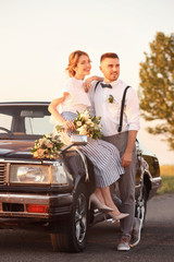 Canvas Print - Happy wedding couple and decorated car outdoors