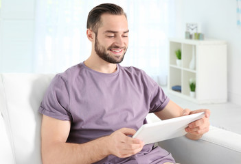 Wall Mural - Young man searching information using tablet at home