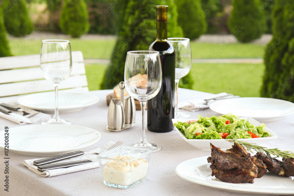 Delicious steak with wine on festive table outdoors