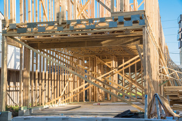 Wall Mural - Close-up wooden frame house under construction at Boulevard Oaks in Houston, Texas, USA. Upper structure rest on wide joists with floor platform framing of frame panels and temporary struts, log piles