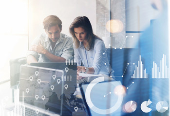 Wall Mural - Concept of digital diagram,graph interfaces,virtual screen,connections icon.Two young coworkers working on computer at sunny office.Woman pointing on notebook screen. Blurred background.