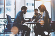 © SFIO CRACHO - Teamwork brainstorming process.Young man working together with partners in modern office loft.Business startup concept.Blurred background.Flares.